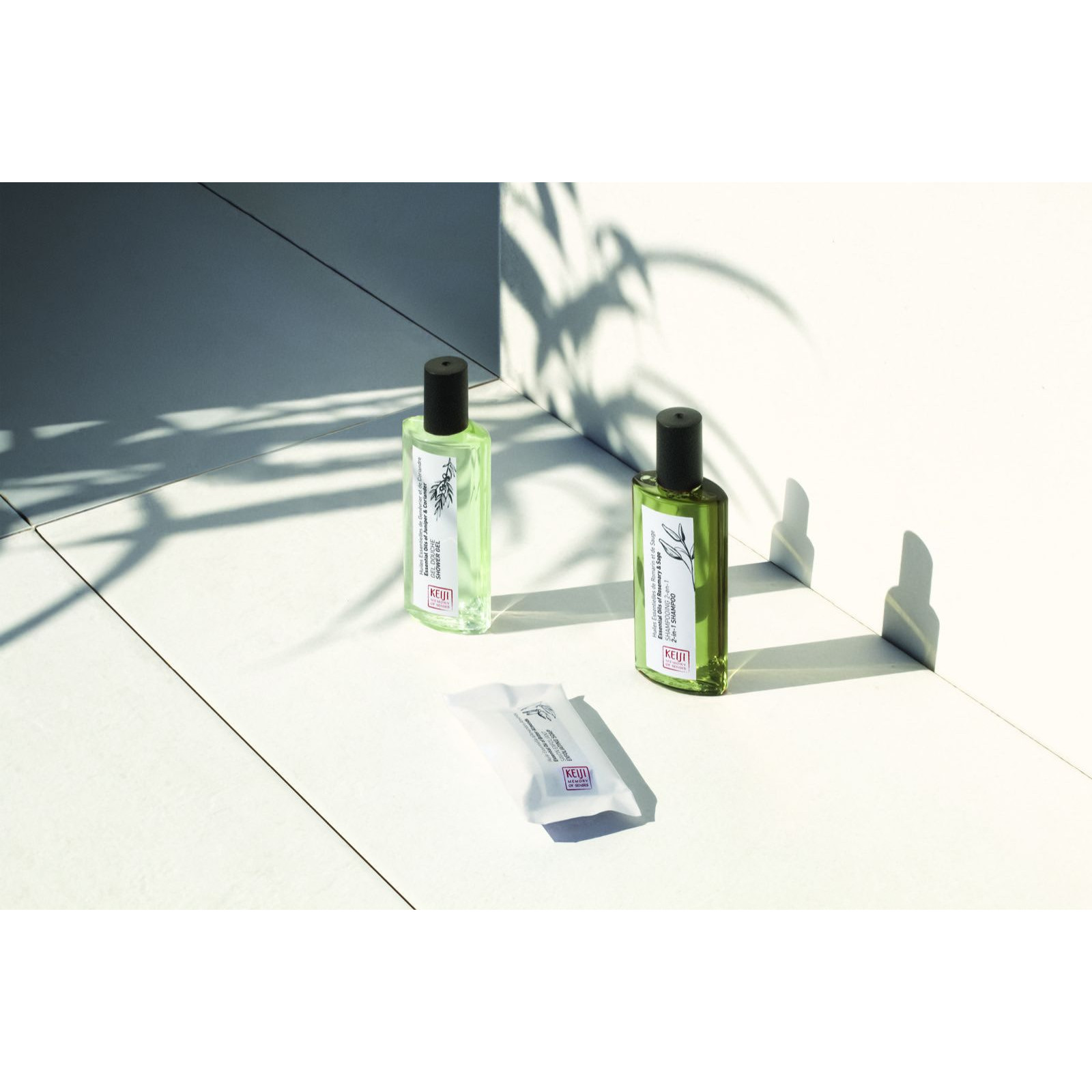 Keiji 40 ml-es flakonok és szappan világos fürdőszobai fényben, pálmalevél árnyékával